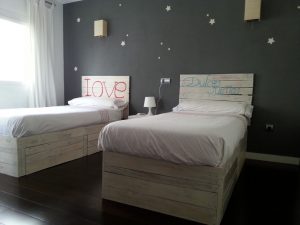Habitación infantil con dos camas individuales hechas con palets
